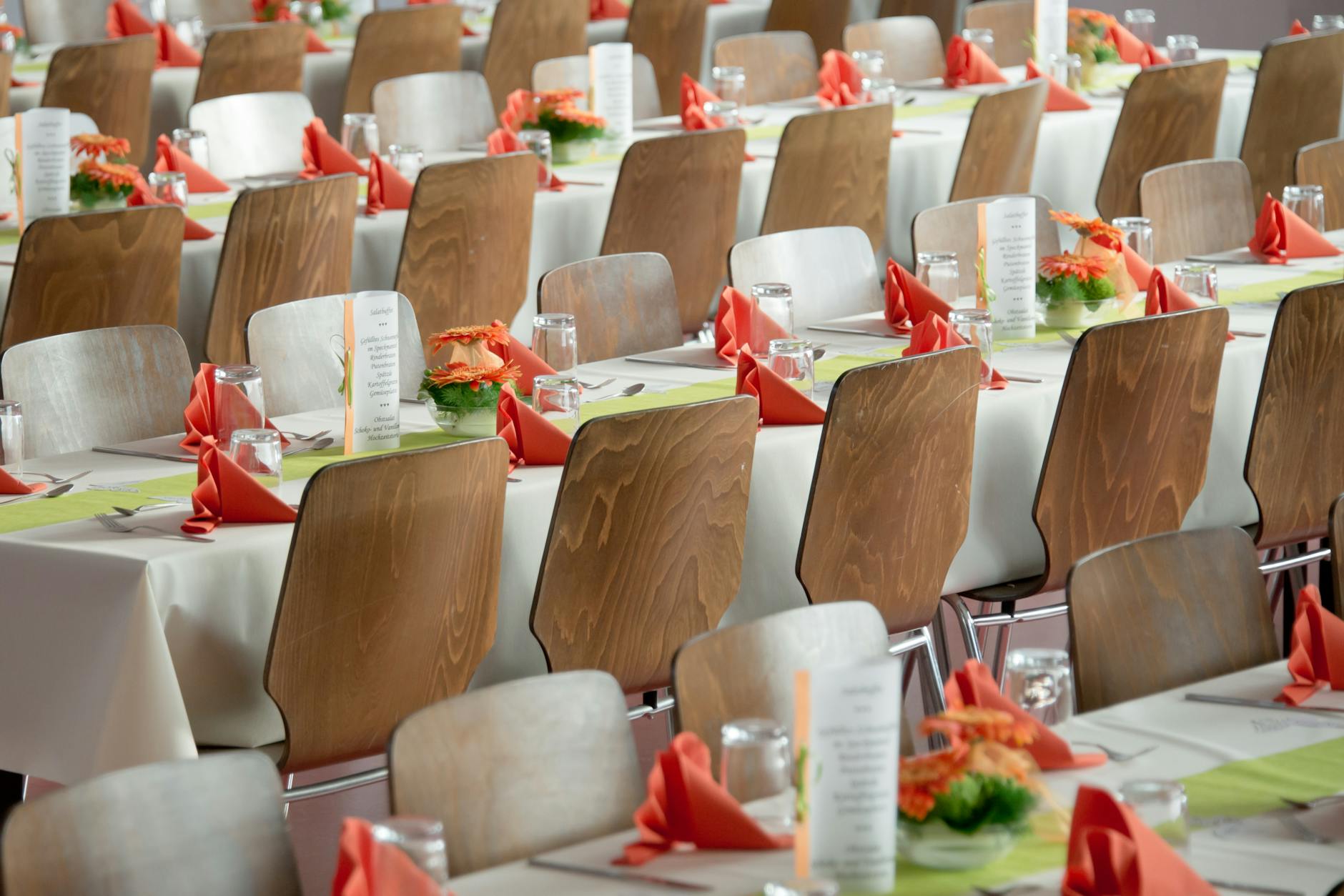 long tables with white cloths and brown chairs formal setting